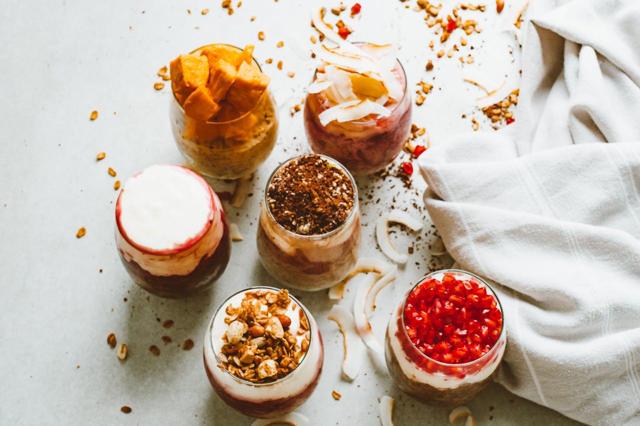 Top-down view of assortment of delicious yogurt parfaits topped with fresh fruits and granola.